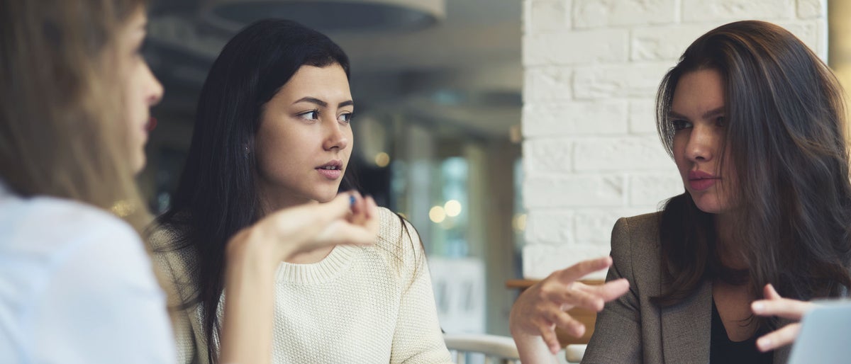 Group of female business partners having discussion about new project making creative solutions together.Skilled colleagues sharing ideas while brainstorming on informal meeting in coffee shop