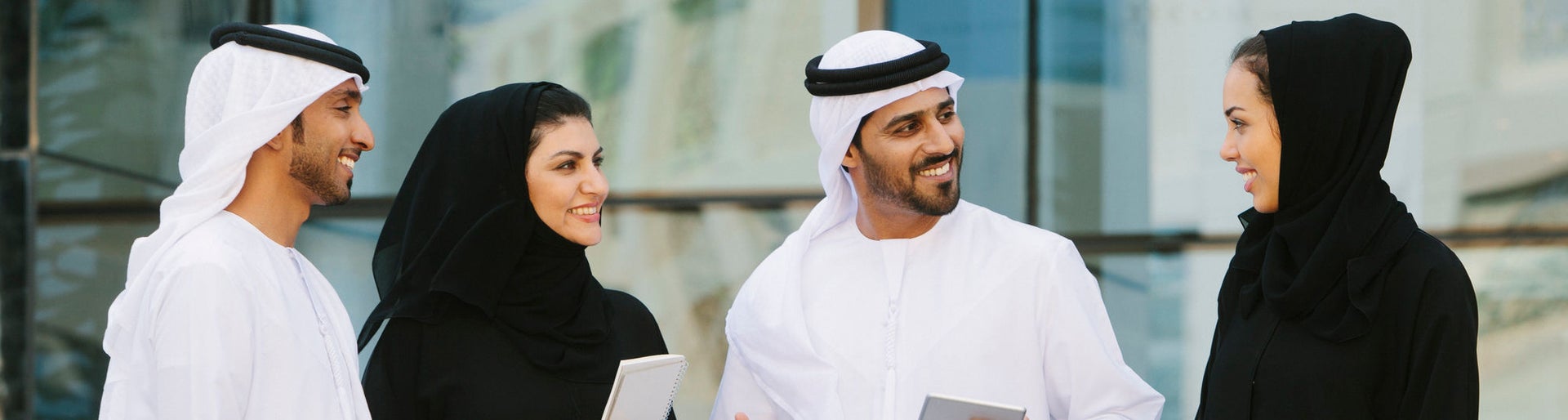 Four arab businesspeople in traditional clothing having a discussion in front of a  office building.