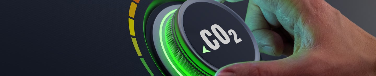 Lower CO2 emissions to limit global warming and climate change. Concept with manager hand turning knob to reduce levels of CO2. New technology to decarbonize industry, energy and transport