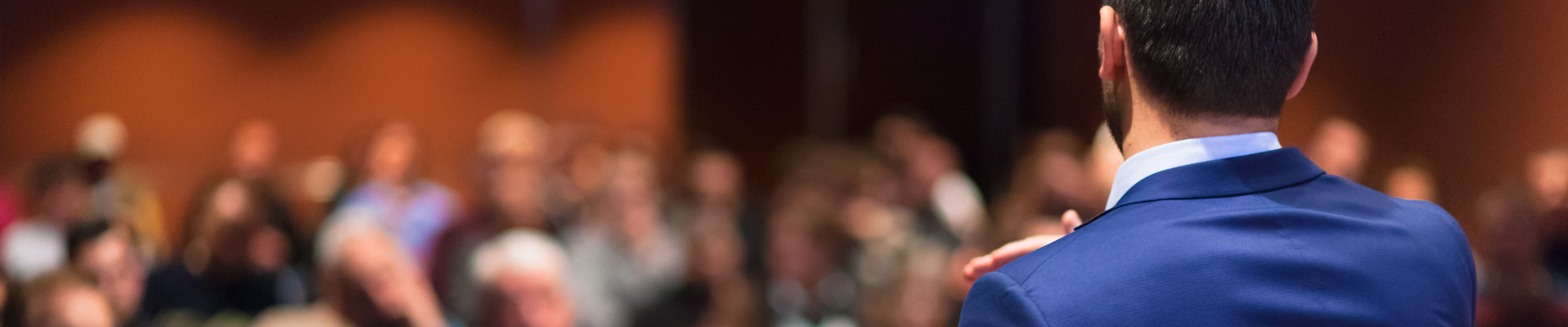 Rear view of speaker giving a talk on corporate Business Conference. Audience at the conference hall. Business and Entrepreneurship event. Panoramic composition.