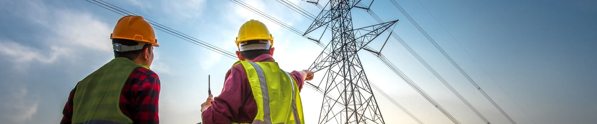 Picture of two electrical engineers using a notebook computer standing at a power station to view the planning work by producing electrical energy at high voltage electrodes.