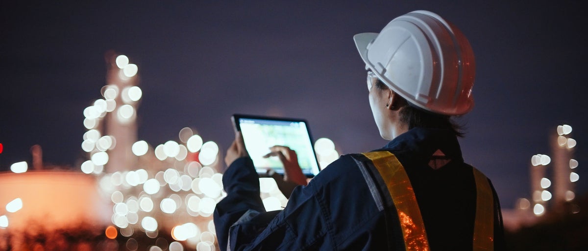 Asian Inspection engineers working with laptop of gas refinery plant and refinery oil factory industry at night.