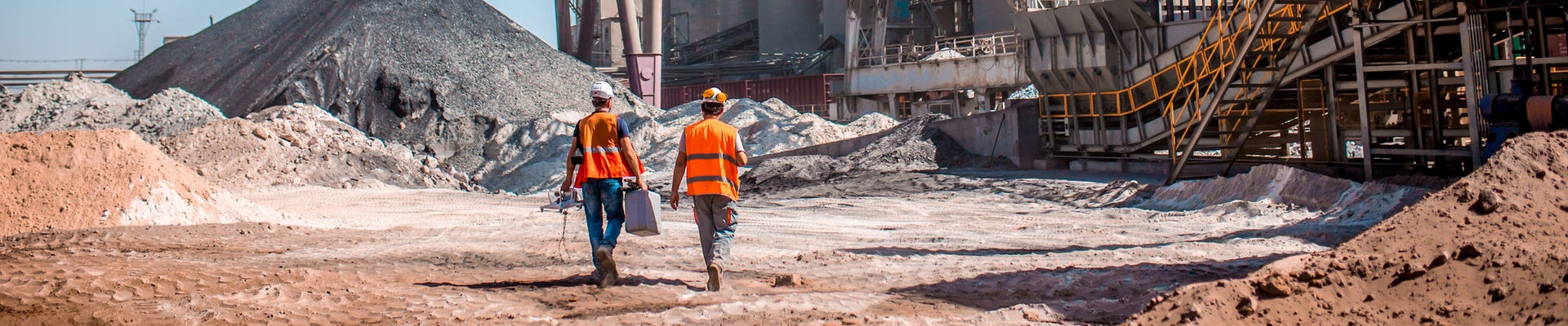 People are working in the industry. Modern technologies work at a cement plant. Technological work on the production of cement. Working atmosphere with copy space. Heaps of sand and soil raw materials