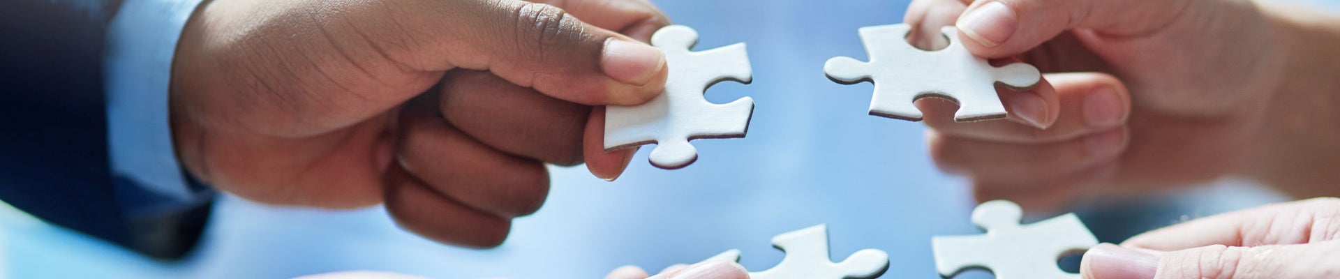 Cropped shot of people putting four puzzle pieces together