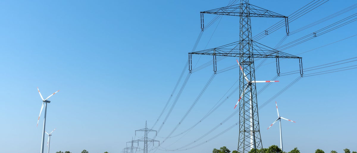 Overhead power lines in a field of blooming oilseed rape seen in rural Germany