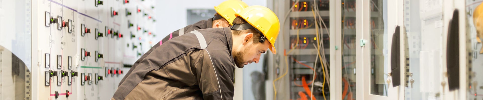 Two maintenance engineers inspect relay protection system with laptop computer. Bay control unit. Medium voltage switchgear