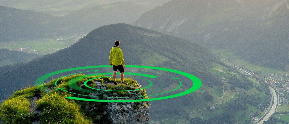 Hiker stands and enjoys valley view from hilly viewpoint. Traveling on hill peaks landscape. Sport, tourism and hiking concept. Watching sunset.