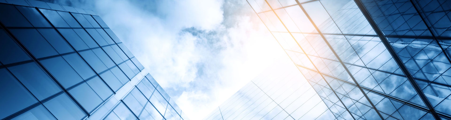 view of a contemporary glass skyscraper reflecting the blue sky