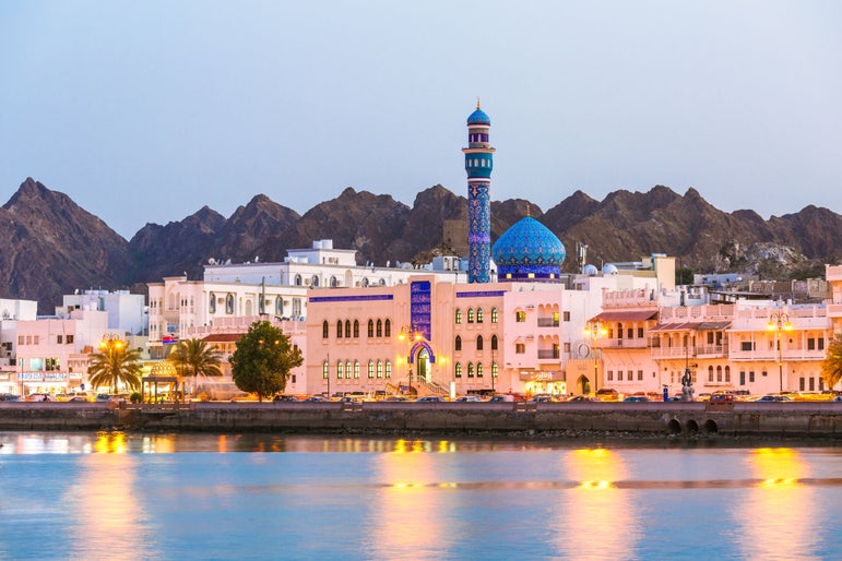 Oman, Muscat. Cityscape of Mutrah harbour, at dusk