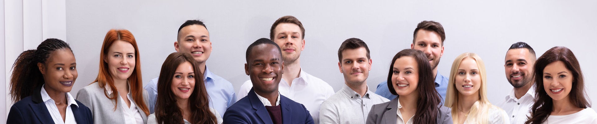 Group Of Young Successful Multi-ethnic Businesspeople Standing In Office Looking At Camera