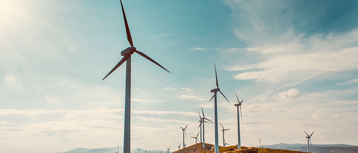 Wind turbines on beautiful sunny summer autumn mountain landsape. Curvy road through mountain Eolic park. Green ecological power energy generation. Wind farm eco field