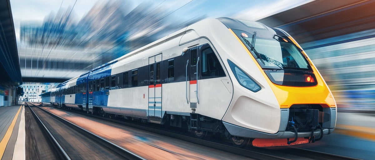 High speed train in motion on the railway station at sunset. Modern intercity passenger train with motion blur effect on the railway platform. Industrial. Railroad in Europe. Commercial transportation