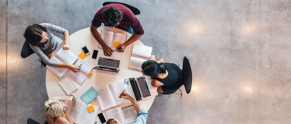 Top view of group of students sitting together at table. University students doing group study.