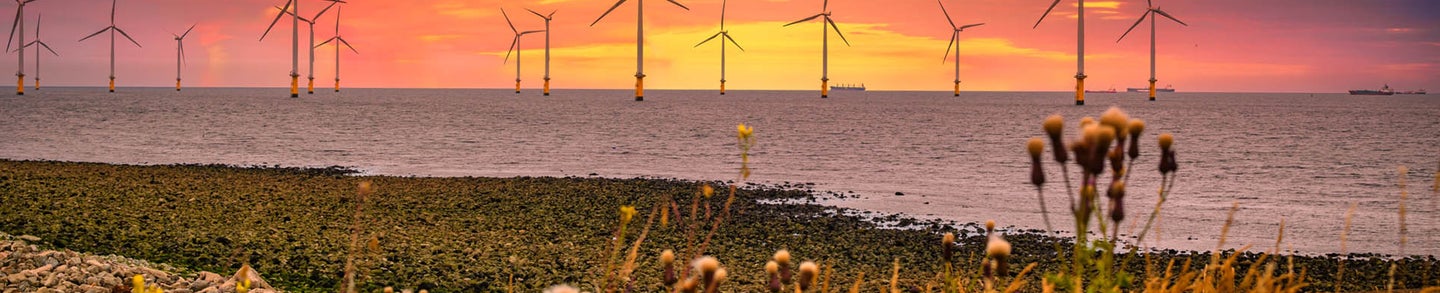 Offshore Wind Turbine in a Wind farm under construction off the England coast at sunset