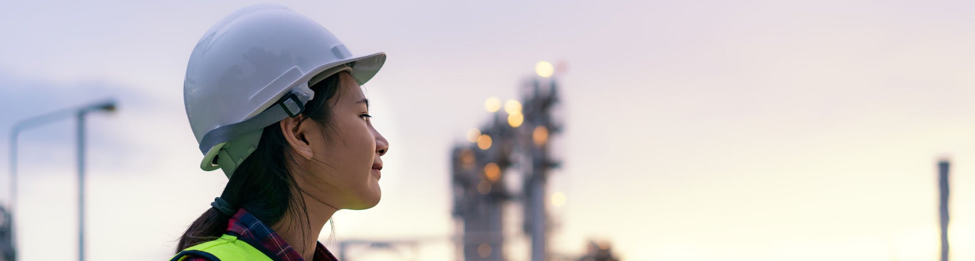 Asian woman petrochemical engineer working at night with laptop Inside oil and gas refinery plant industry factory at night for inspector safety quality control.