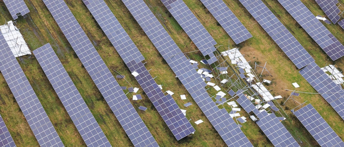 An aerial view taken from a helicopter of a damaged solar farm in Britain. Stormy weather and strong winds have broken and destroyed solar panels. Photovoltaic panels scattered across a field. 