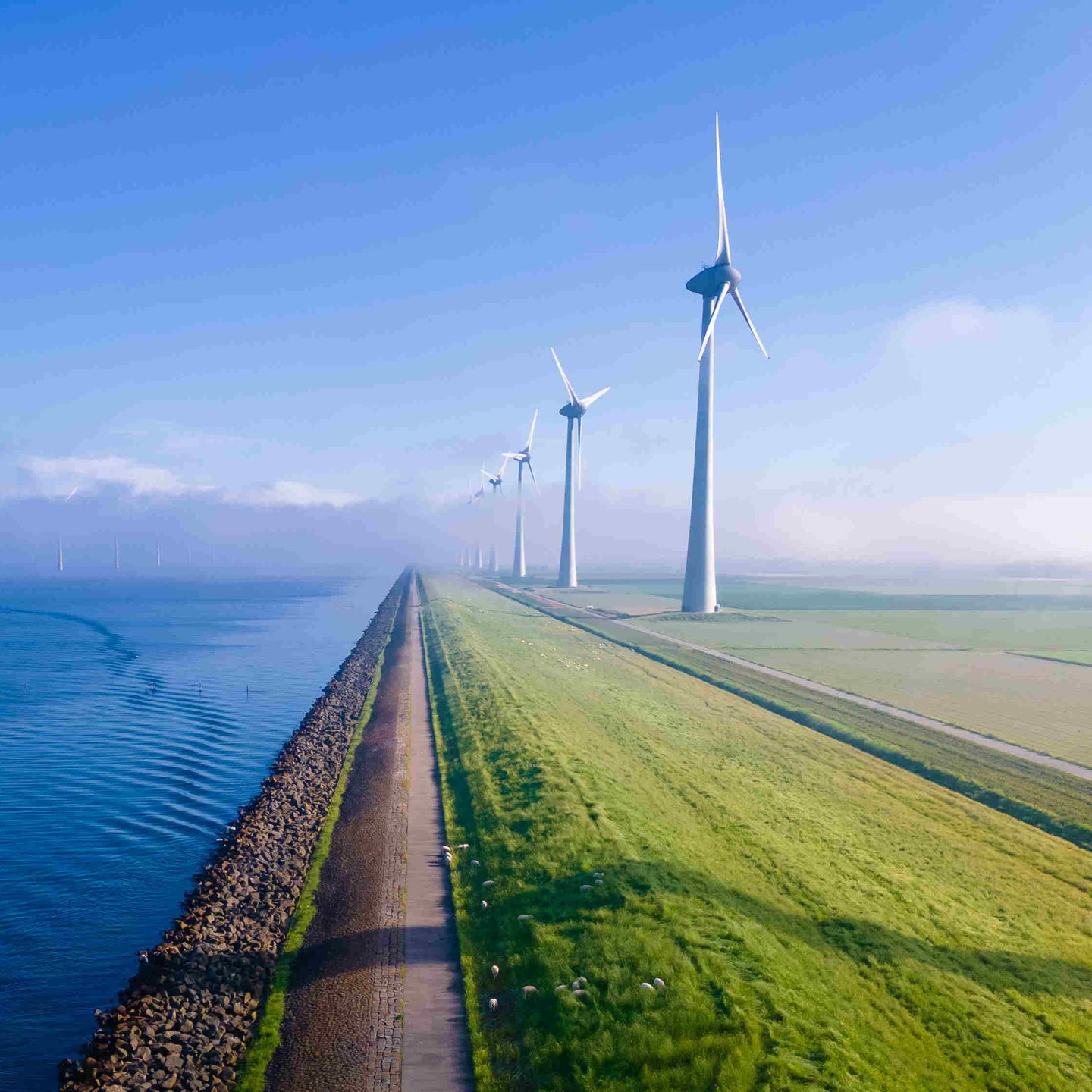 offshore windmill park with clouds and a blue sky, windmill park in the ocean aerial view with wind turbine Flevoland Netherlands Ijsselmeer. Green energy 