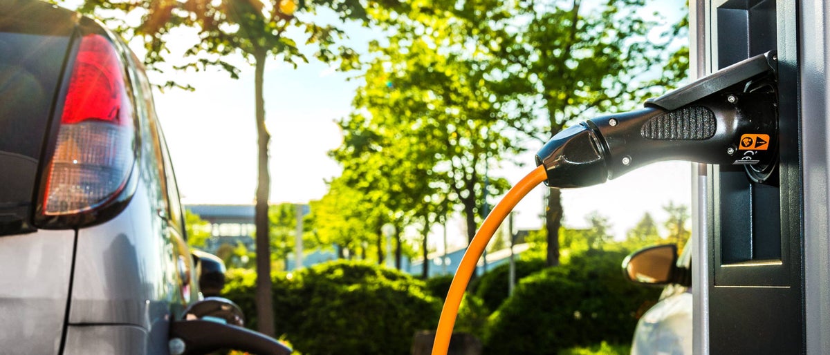 Electric Car on a charging station with back and light plug detail, electric mobility