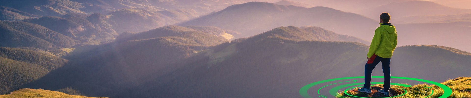 Sporty man on the mountain peak looking on mountain valley with sunbeams at colorful sunset in autumn in Europe. Landscape with traveler, foggy hills, forest in fall, amazing sky and sunlight in fall
