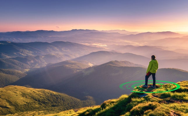 Sporty man on the mountain peak looking on mountain valley with sunbeams at colorful sunset in autumn in Europe. Landscape with traveler, foggy hills, forest in fall, amazing sky and sunlight in fall