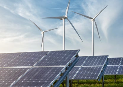 solar panels and wind generators under blue sky on sunset