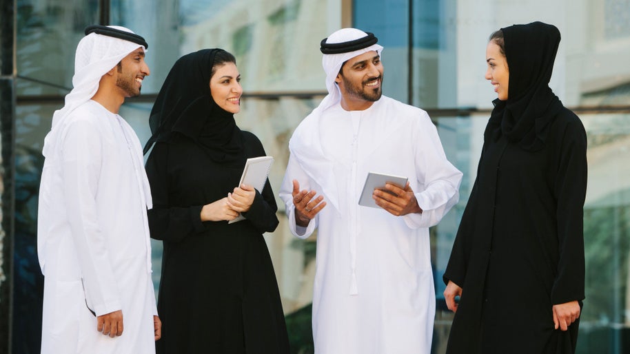 Four arab businesspeople in traditional clothing having a discussion in front of a  office building.